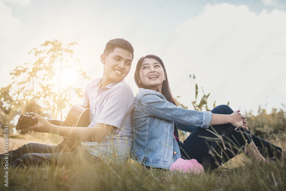 Thai Asian people, happy love couple playing guitar in park Thai Asian people, happy love couple playing guitar in park