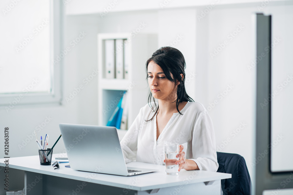 Business Woman Reading an Email and Holding a Glass with Water Business Woman Reading an Email and Holding a Glass with Water