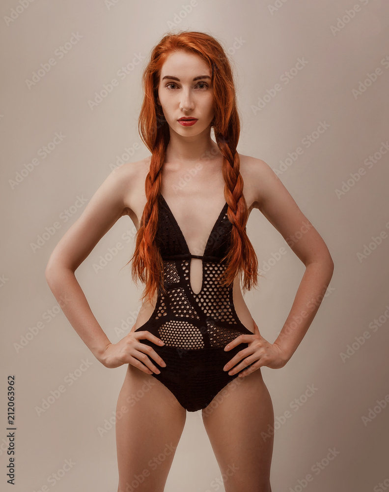 Model shoot in studio. Skinny girl with red long hair posing in the black  knitted swimsuit bikini in warm tones Stock Photo | Adobe Stock