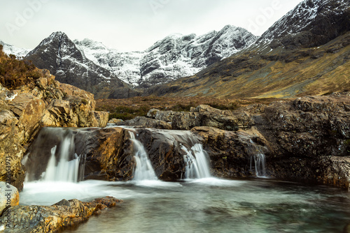 Fairy Pools waterfall  River Brittle . Glenbrittle  Isle of Skye  with snow covered mountains in  the background