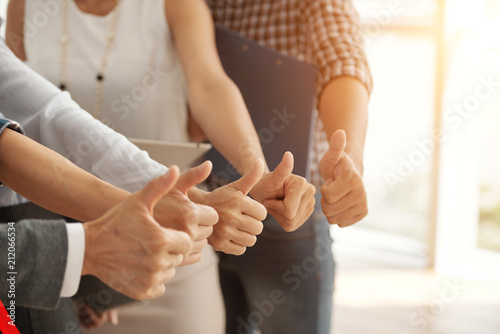 Close-up of business team showing thumbs up together