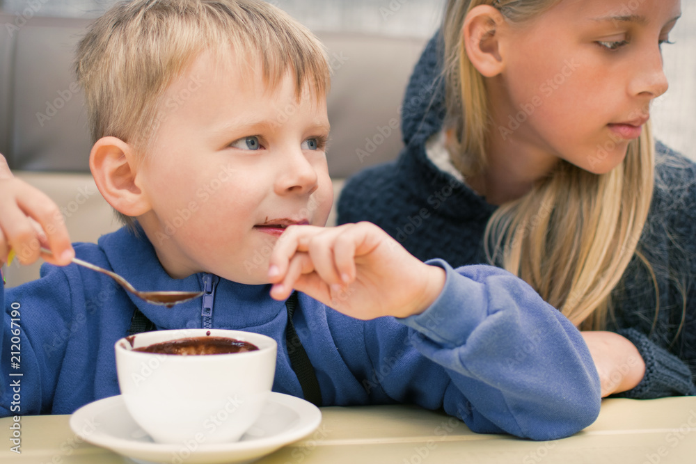 A small boy of 3-5 years old eats hot chocolate in a cafe, restaurant. A small boy of 3-5 years old eats hot chocolate in a cafe, restaurant.