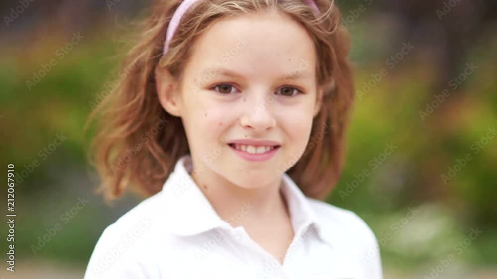 Close up portrait of a beautiful schoolgirl girl. The brown-eyed blond looks fervently into the camera and straightens her curly hair Close up portrait of a beautiful schoolgirl girl. The brown-eyed blond looks fervently into the camera and straightens her curly hair
