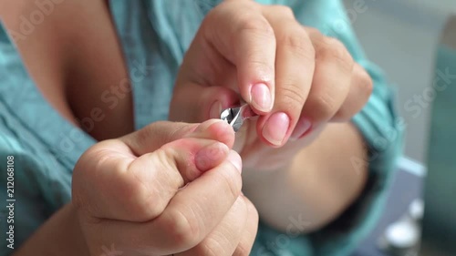 Woman cutting cuticle with manicure tweezers close up. Manicure and nail care concept. Woman making home manicure. photo