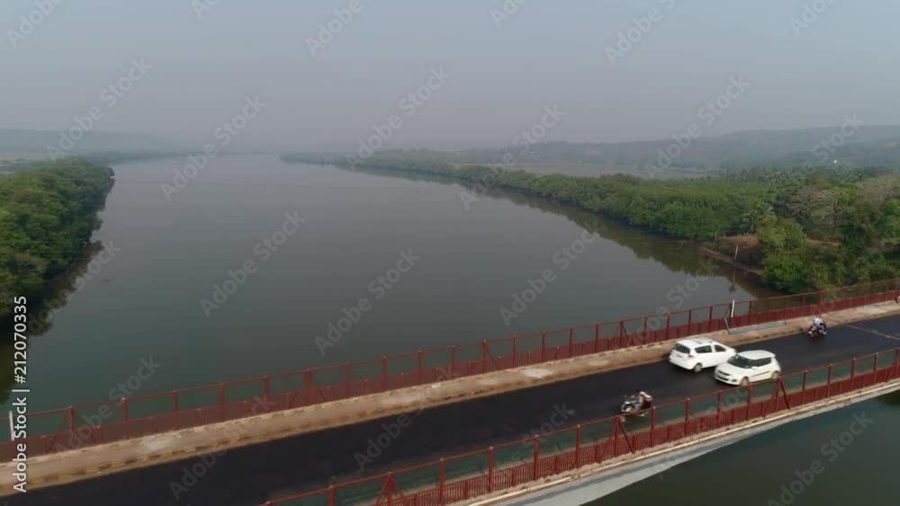Aerial view. Flying over the bridge, cars moves on a large concrete bridge across the Zuari river in Goa, India. Aerial view. Flying over the bridge, cars moves on a large concrete bridge across the Zuari river in Goa, India.
