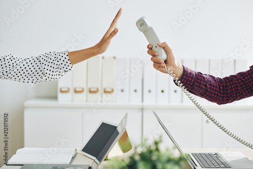 Fotografija Crop man outstretching telephone handset to woman showing stop gesture and rejec
