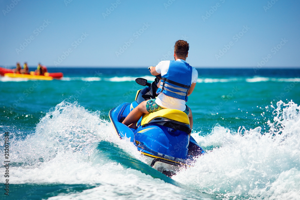 young adult man running the wave on jet ski during summer vacation