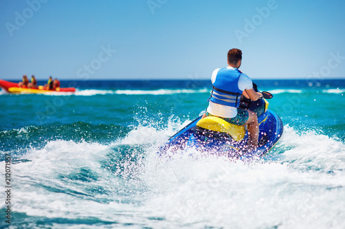 young adult man running the wave on jet ski during summer vacation photo