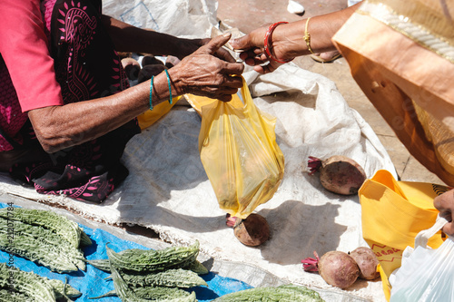 India. Indian people buy and sell fruits and vegetables on the market right on the ground, check products and give cash to each other.