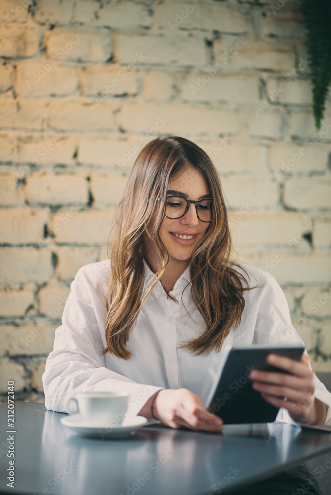 Young modern woman sitting in cafe and using tablet. Young modern woman sitting in cafe and using tablet.