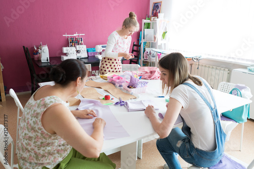 Fashion designers at work. Three cheerful women working at fashion design studio