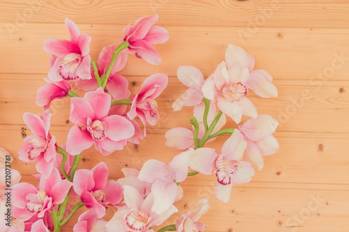 bunch of artificial blooming orchid flowers on wooden background. Interior decoration.