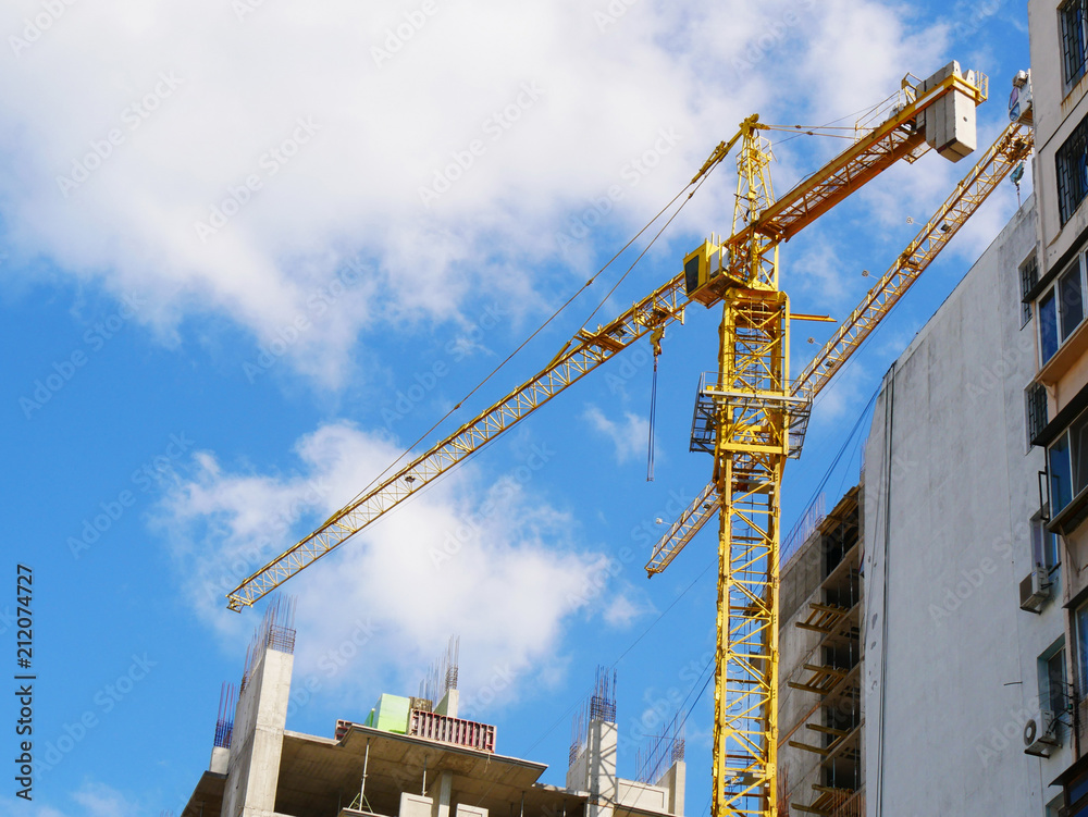Construction cranes near building. Construction site against blue sky Construction cranes near building. Construction site against blue sky