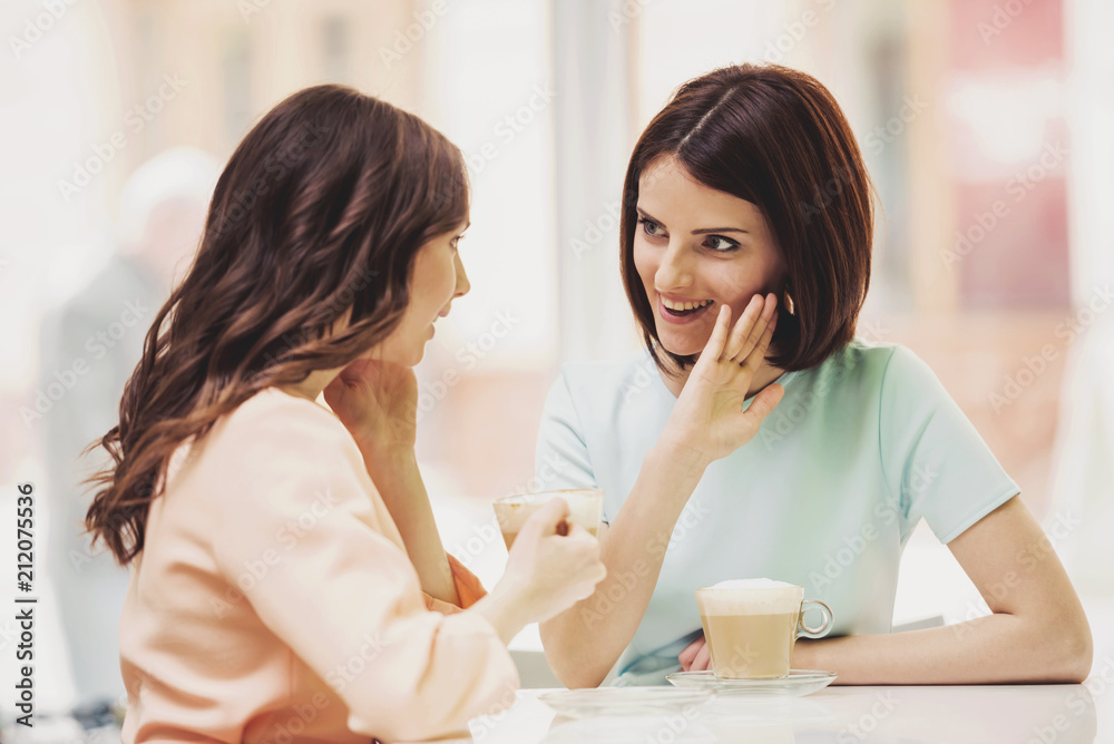Two Girls Chatting in Cafeteria with Cups of Coffee. Two Girls Chatting in Cafeteria with Cups of Coffee.