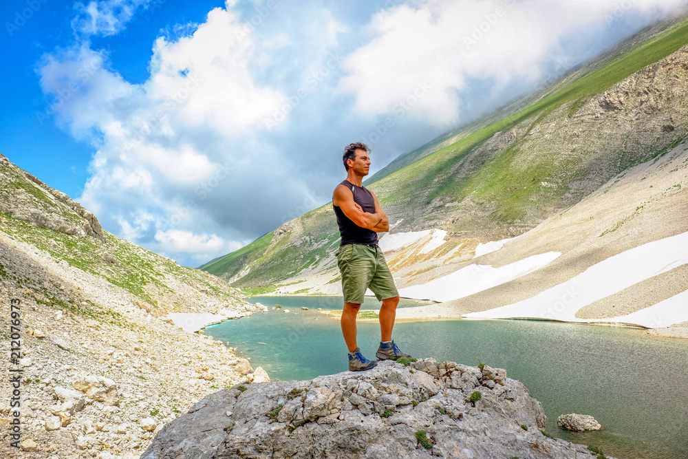 Man standing over a big stone after a trekking to  high altitude lake (Pilato lake)  in the National Park of the Sibillini Mountains in Italy