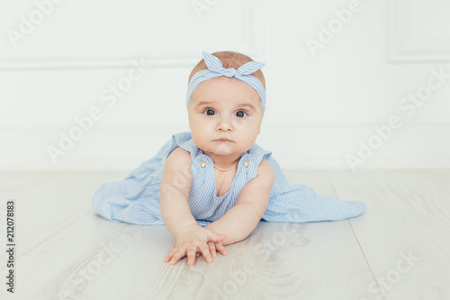 Cute baby on white background.Close up head shot of a caucasian baby girl, six months old baby in blue dress looking at camera