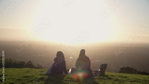 4K Young People having picnic on hill overlooking big city at sunset 4