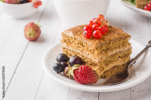 Honey cake with strawberries, mint and currant, a Cup of tea on a light background