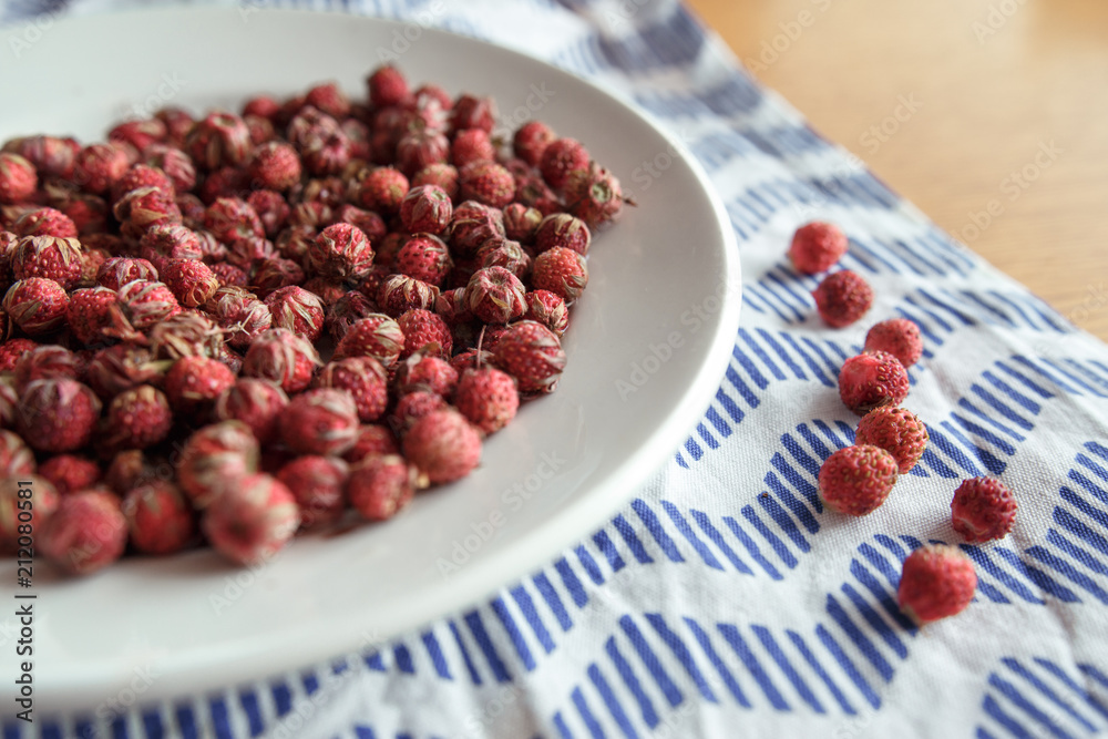 Red field strawberries on white plate on wooden table Red field strawberries on white plate on wooden table