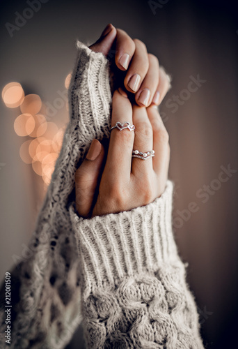 Hands with vintage rings on golden bokeh lights background
