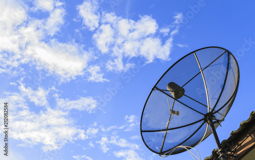 Satellite dish and TV antennas on the roof with blue sky background.