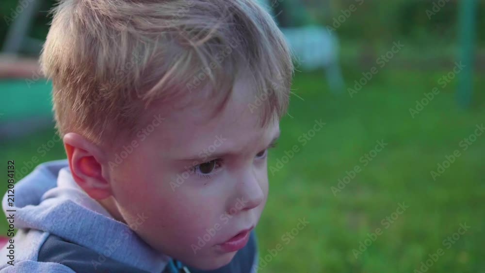 A little boy is lying and playing on the lawn on a hot summer day. Child actively spend their leisure time A little boy is lying and playing on the lawn on a hot summer day. Child actively spend their leisure time