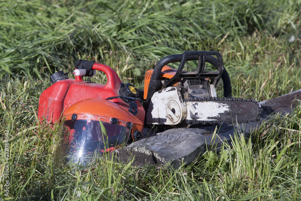 Chainsaw and protective helmet of lumberjack lie on sawn wood. concept is to cut trees at altitude. Chainsaw and protective helmet of lumberjack lie on sawn wood. concept is to cut trees at altitude.