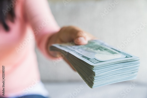 Soft focus on woman hands proposing money us dollar bills to you.