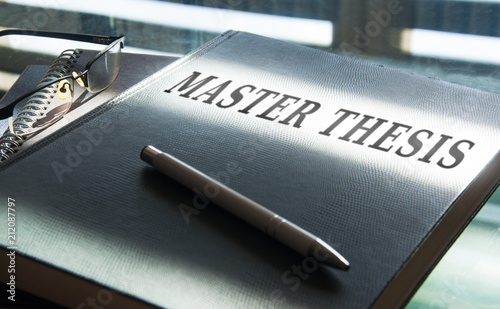 a mastest thesis in being written on desk photo