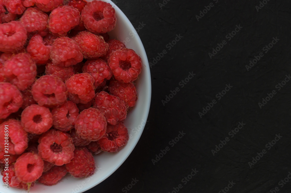 White ceramic plate full of juicy ripe raspberries White ceramic plate full of juicy ripe raspberries