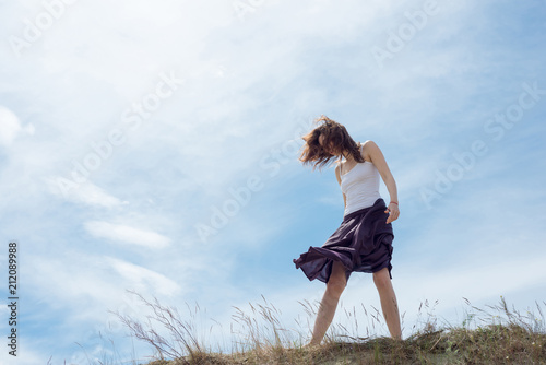 Woman in a dress is standing on a sand hill