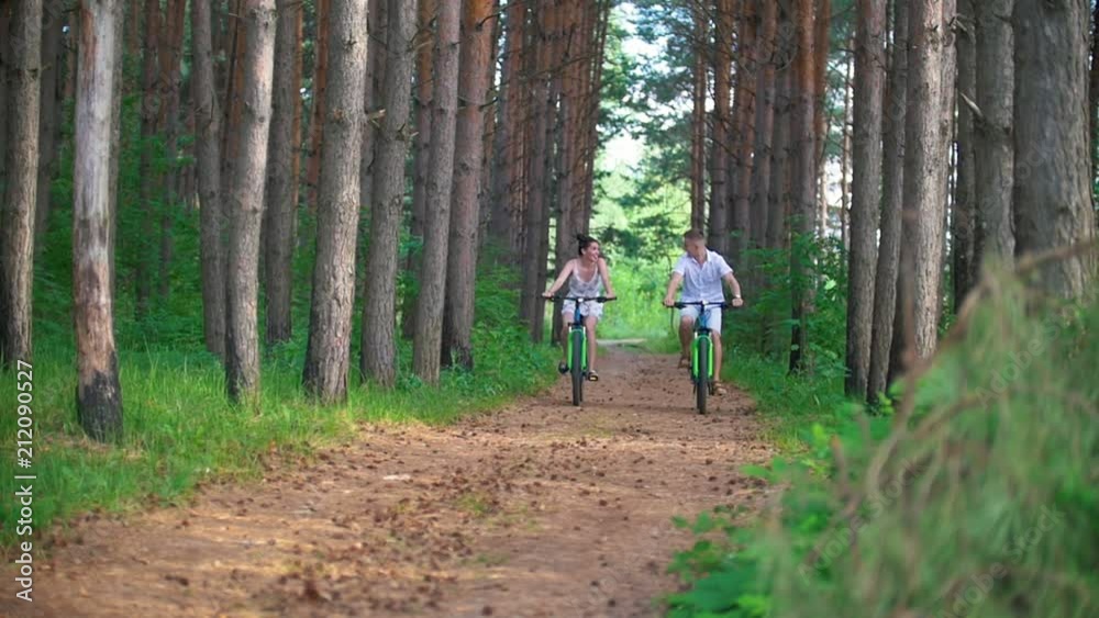 Happy couple cycling on the path in the pine forest Happy couple cycling on the path in the pine forest