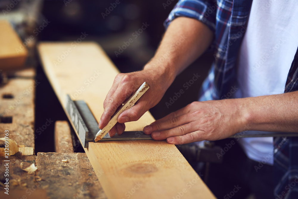 A carpenter uses a framing square in a carpentry shop.