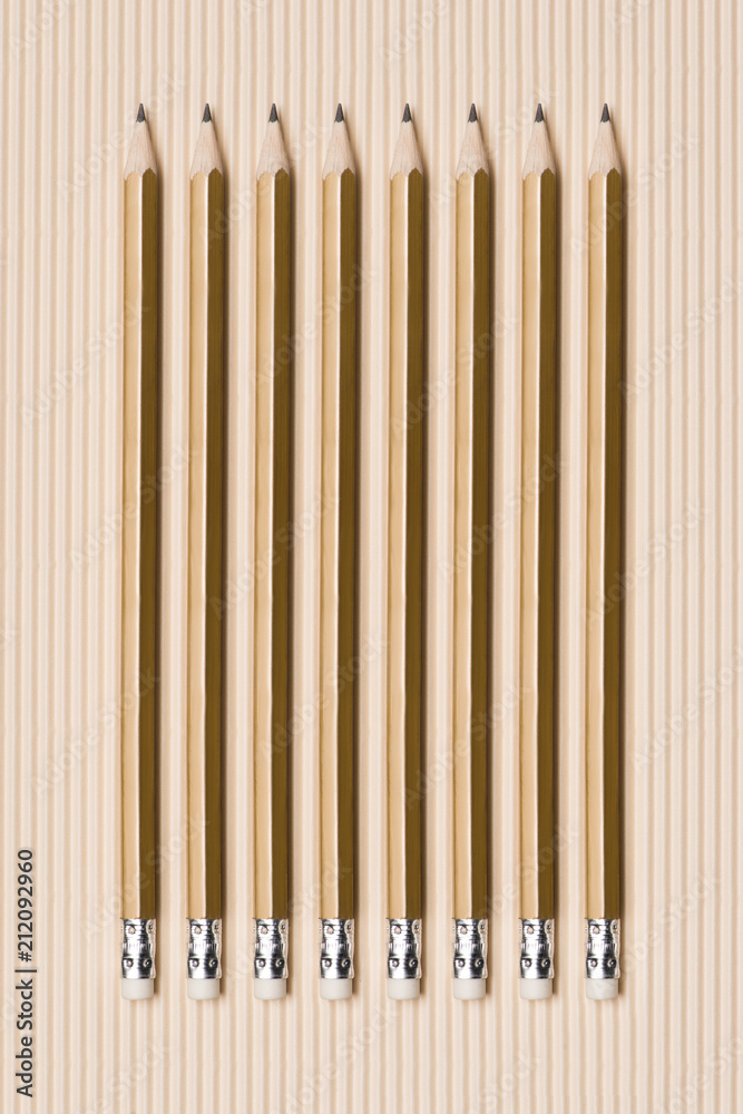 top view of graphite pencils with erasers placed in row on beige