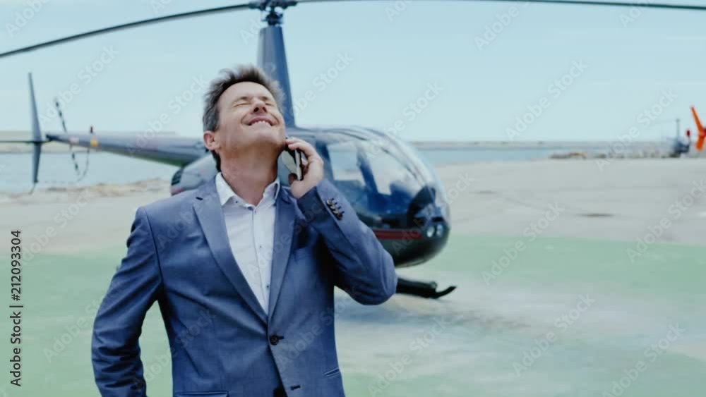 Businessman talking on cellphone near private helicopter Businessman talking on cellphone near private helicopter