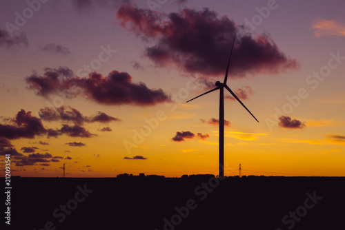 Wind turbines for electrical power generation in Normandy, France. Countryside and industrial landscape at sunset. Renewable energy sources. Environment friendly energy production