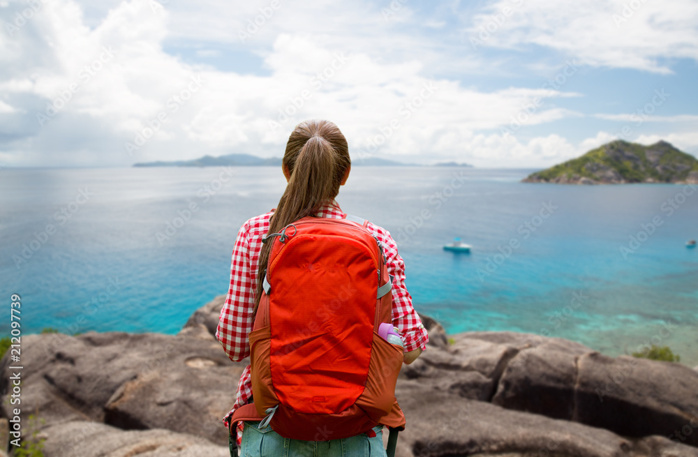 adventure, travel, tourism, hike and people concept - young woman with backpack over background of seychelles island in indian ocean