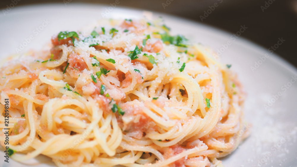 Close-up image of spaghetti sauce tarako which made from fresh cod fish in Japan and mixed with Thai coriander on the top of white plate and famous italian-japanese menu dish in Thailand restaurant Close-up image of spaghetti sauce tarako which made from fresh cod fish in Japan and mixed with Thai coriander on the top of white plate and famous italian-japanese menu dish in Thailand restaurant
