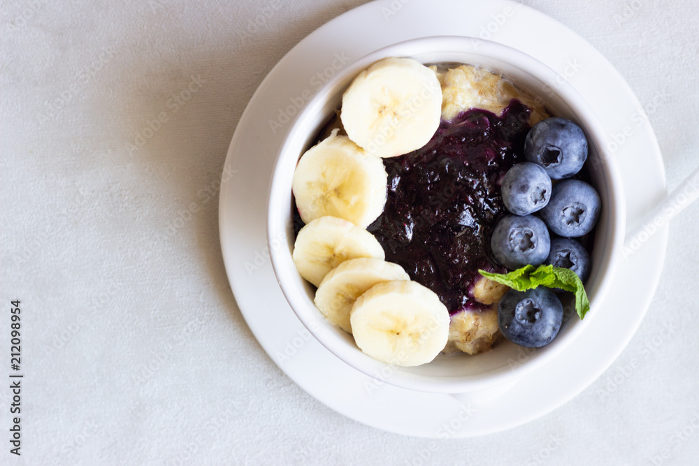 Porridge in a bowl with blueberries, banana and mint. Healthy breakfast concept Porridge in a bowl with blueberries, banana and mint. Healthy breakfast concept