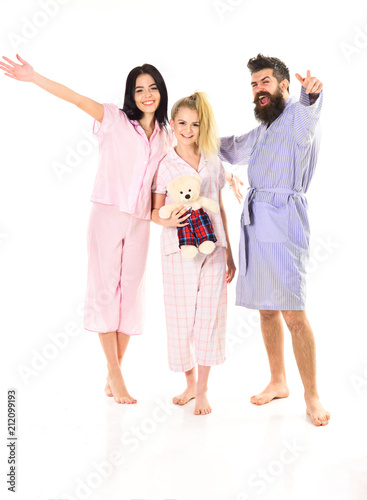 Man with beard and mustache, cute blonde and brunette girls with toy bear full of energy. Girls with bearded macho in pajamas and robe in morning, isolated white background. Good mood concept.