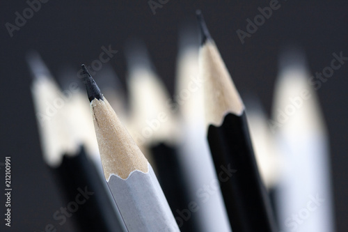 Macro picture of grahite pencils on black and white pencils background, selective focused on white sharpened pencil.  photo