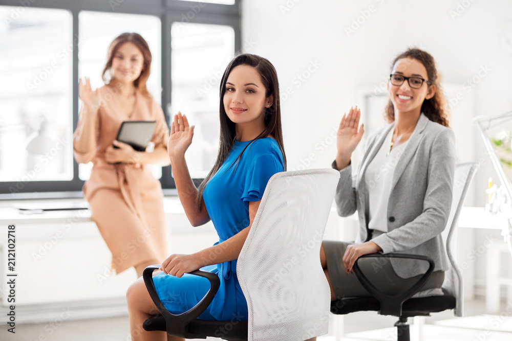 business and people concept - smiling businesswomen waving hands at meeting in office business and people concept - smiling businesswomen waving hands at meeting in office