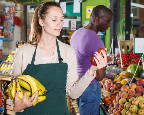 Seller woman is helping man choose exotic fruits