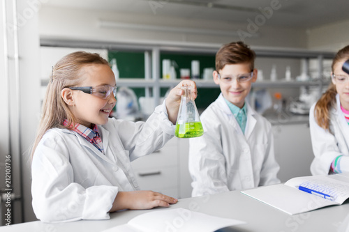 education  science and children concept - kids with test tubes studying chemistry at school laboratory