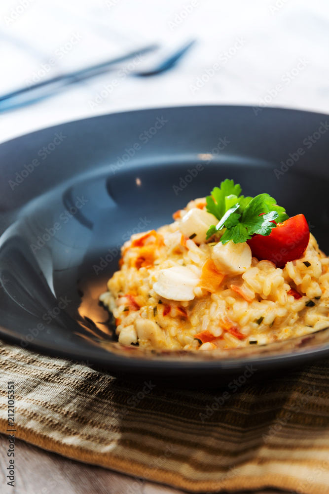 Tasty risotto with Scallops, fresh herbs vegetables on a white plate Tasty risotto with Scallops, fresh herbs vegetables on a white plate
