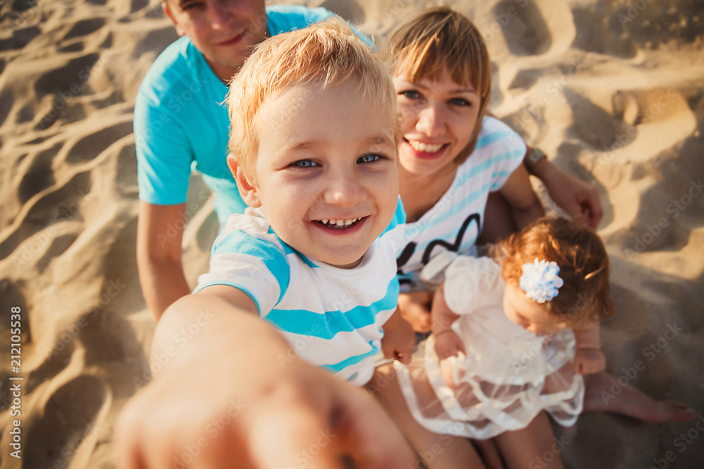 Close up of young happy loving family with small kids in the middle, having fun at beach together near the ocean, happy lifestyle family concept Close up of young happy loving family with small kids in the middle, having fun at beach together near the ocean, happy lifestyle family concept