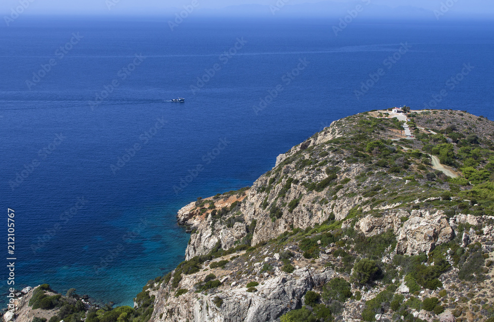 Seascape with a ship on the blue sea and a small Greek house at a strong distance on the island of Rhodes