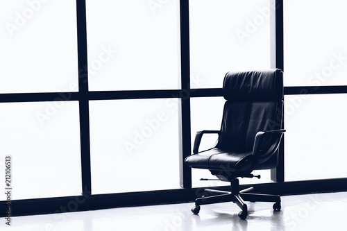 Black executive leather chair in empty office space with large window ,copy space.