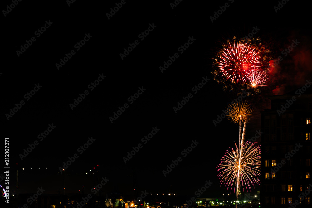A Fourth of July fireworks display explodes over the waterfront in the city center of Norfolk Virginia, in the context of buildings, apartments, and dwellings A Fourth of July fireworks display explodes over the waterfront in the city center of Norfolk Virginia, in the context of buildings, apartments, and dwellings