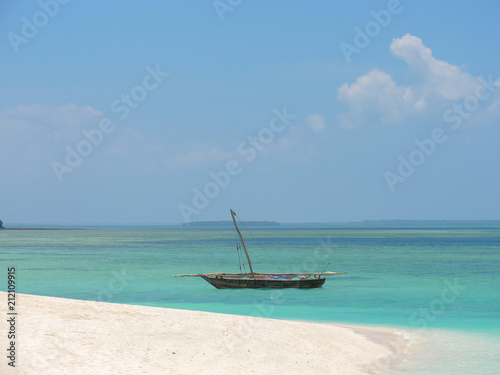 Fisherman fishing and sails on a wooden boat on clear blue water along a tropical exotic beach in Africa. Indian Ocean, Zanzibar © sefoma